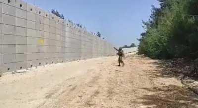 IDF Soldier slingshots a projectile over Lebanon barrier wall