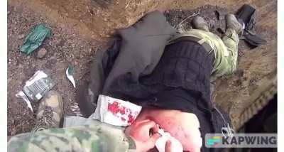 Russian medic bandages up a large back laceration from artillery, as he is finishing up another artillery shell hits nearby