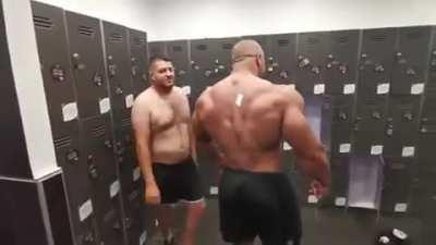 Bodybuilder tries reaching sticker on his back.