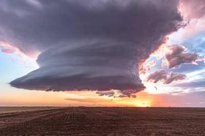 Tornadic storm supercell rotates and marches along the Texas prairie at sunset