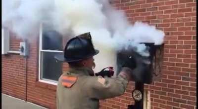 Firefighter demonstrates how applying moisture around an enclosure helps extinguish a fire inside