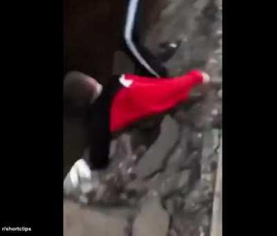 Pedestrian looks into a deep hole, then loses balance