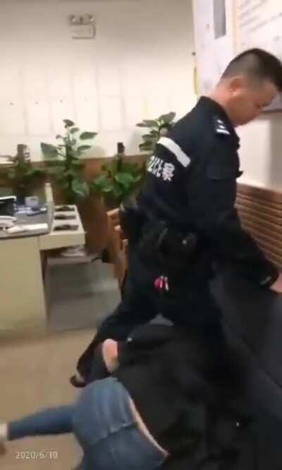 Police in China subduing woman by pushing his knee on her neck