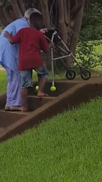 Little boy takes his time to help elderly woman up the stairs