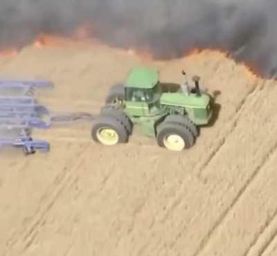 Farmer cultivates field to prevent fire spread