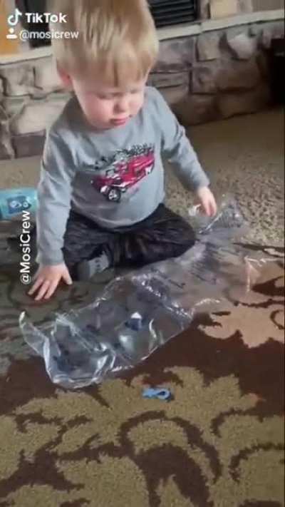 Baby popping bubble wrap with his head