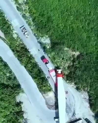 Transporting a massive turbine blade up a winding mountain road.