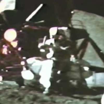 An astronaut dropping a hammer and a feather on the moon at the same time.