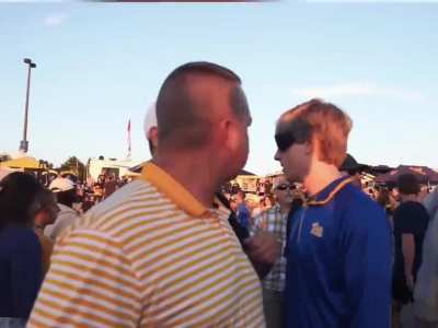 A guy is going to college football games and is triggering sports fans by wearing the opposing team's gear.