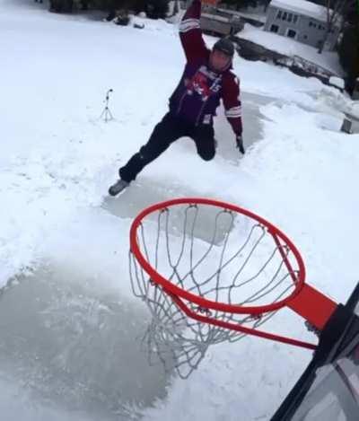 Guy dunks the ball while ice skating