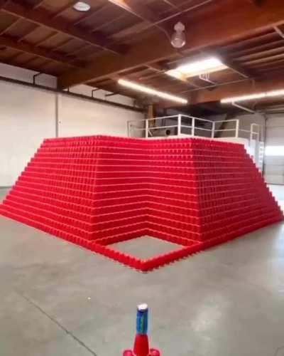 Stacking plastic cups to make a giant pyramid and ramming it with a car for big fun