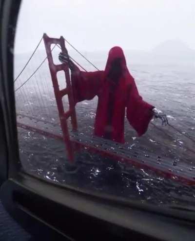 This CGI render of a giant red death holding onto the Golden Gate Bridge