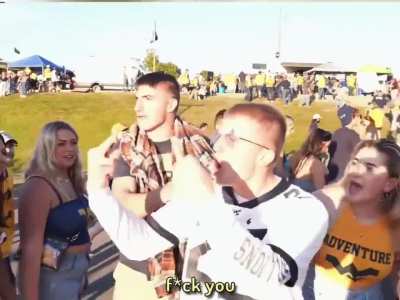 A guy is going to college football games and is triggering sports fans by wearing the opposing team's gear.