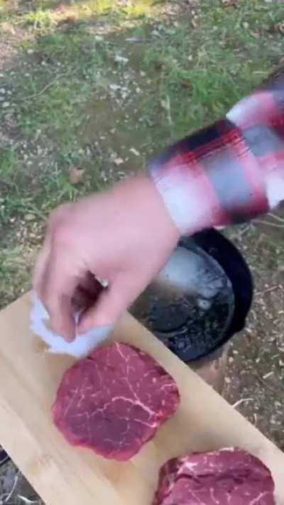 This man cooking surf and turf over a Rocket Stove