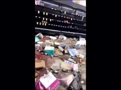 Woman breaks down as she walks through a store which was ransacked by looters