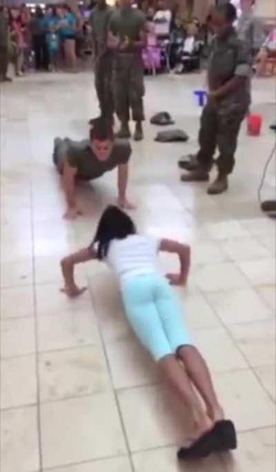 Little girl competes with a marine in a push up challenge.