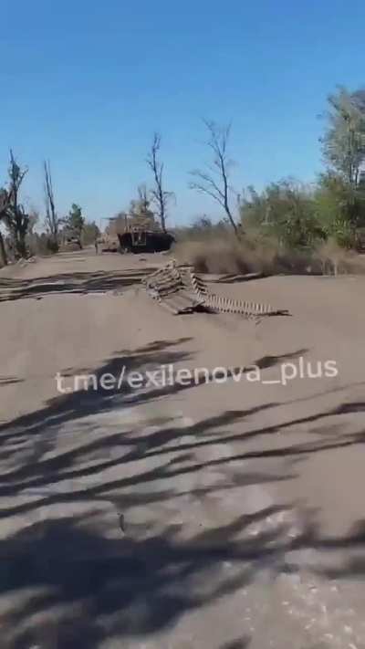 Russian soldiers on motorcycles driving on one of the risky roads. (lot of destroyed equipment visible)