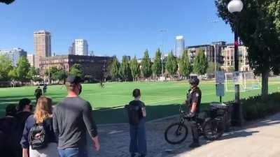 Seattle Police arrest an onlooker as they chase a homeless man through a field.