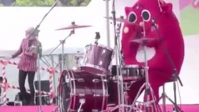 A costumed drummer completely destroying the drums