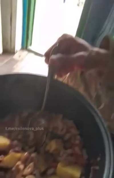 KPA soldier in Russian uniform presenting food on camera and eating it.