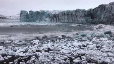 Tourists watch and scramble for cover as a huge chunk of the Breiðamerkurjökull glacier calves. Looks relatively harmless until you see the waves rolling in!