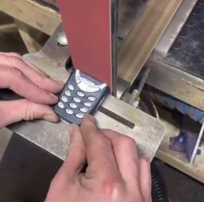 Nokia 3310 getting destroyed by belt sander