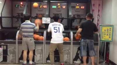 Asian dad locked in on a basketball arcade game