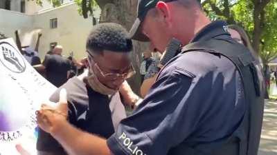 Police officer comforts crying protester