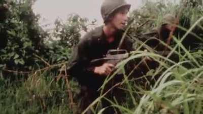 US soldiers in South Vietnam form up in the jungle and duck from a round flying overhead