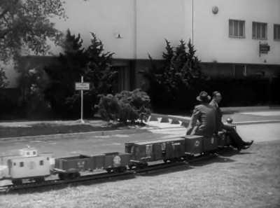 Walt Disney takes a ride on a miniature train through the backlot of Walt Disney Studios