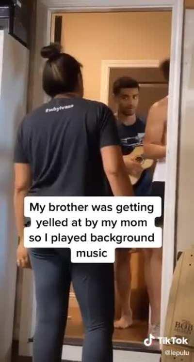 His brother was getting yelled by thier mother so he thought that playing some background music would be a good idea