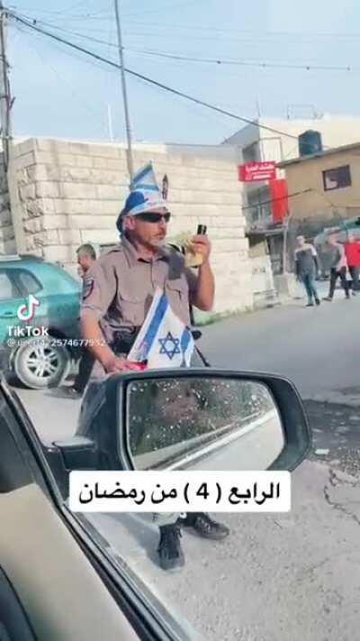 A settler walking around eating and with a bottle of Coca Cola around Palestinians during the holy month of Ramadan.