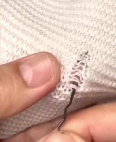 Mending a sweater with a double-ended latch hook. 