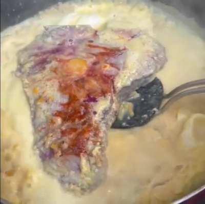 Steak in a frying pan with macaroni , cheese and egg