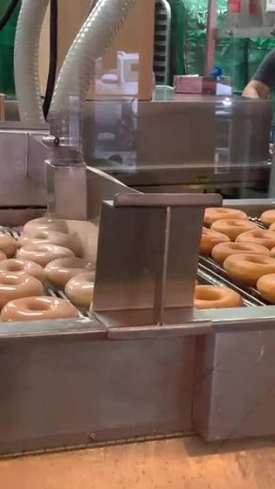 Krispy Kreme doughnuts being glazed. Hot and fresh