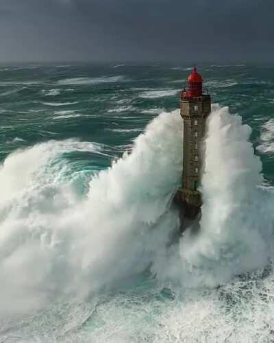 Waves breaking on a lighthouse. Ouessant, France.