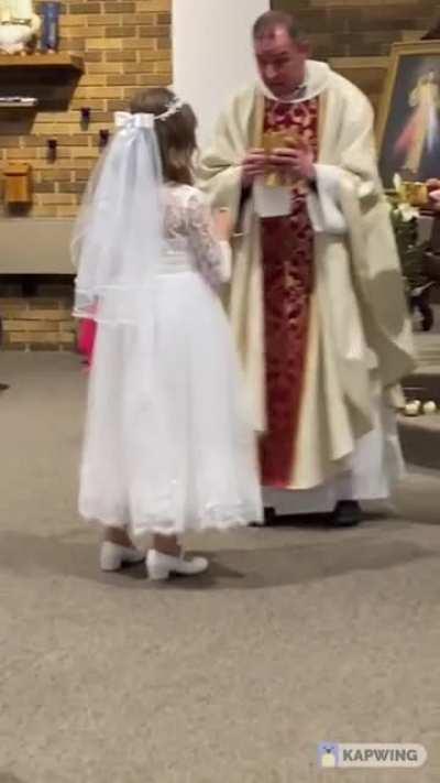 This priest soon realizes that it’s the girl’s first Communion.