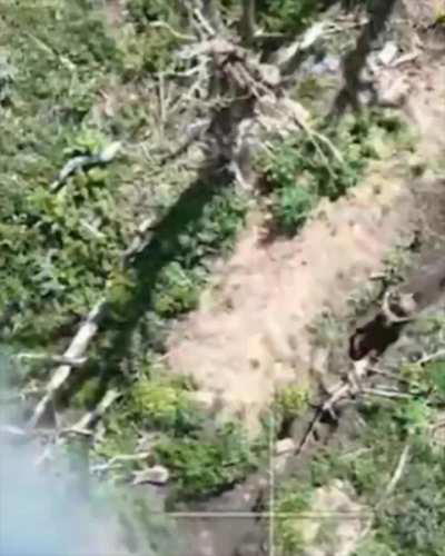 A Russian soldier hitting a Ukrainian FPV drone with a stick