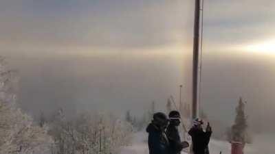 A solar parhelion. It is in the family of halos caused by the refraction of sunlight by ice crystals in the atmosphere.