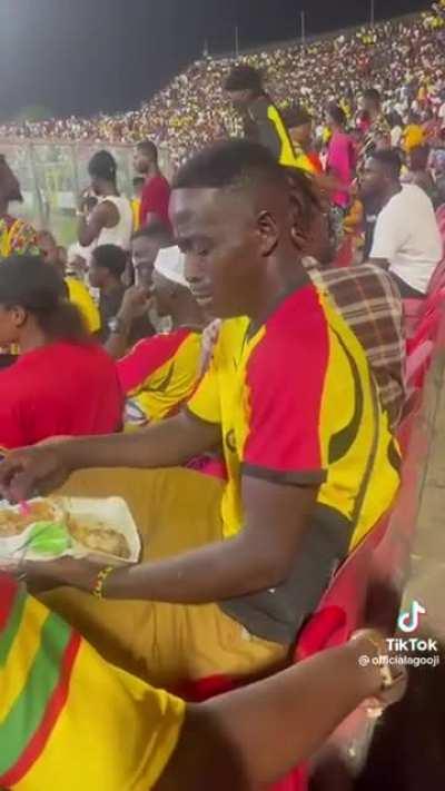 Man in anguish while his team is losing as he tries to force himself to eat his sumptuous meal