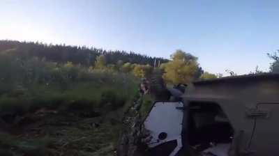 Ukrainian soldiers act quickly to get a camouflage net over their overturned Roshel Senator armored car after an accident.