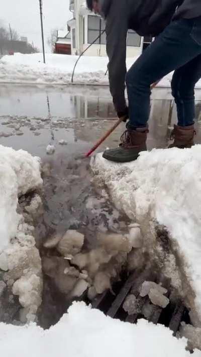 Chipping away ice to clear a storm drain.